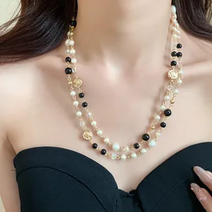 Detail view of elegant long pearl necklace featuring vintage floral coins and black beads