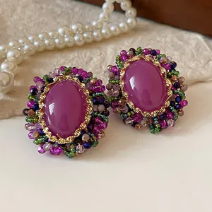 Vista detallada de pendientes vintage de cristal violeta con detalles florales de cuentas