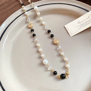 Close-up detail of a long necklace with white pearls and vintage gold flower charms