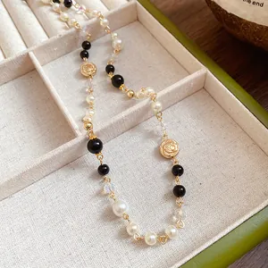 Detailed shot of vintage long necklace with pearls, black beads and gold flower charms
