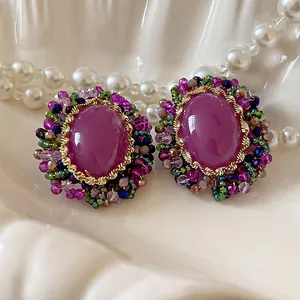 Primer plano de pendientes vintage de cristal púrpura con detalles florales de perlas