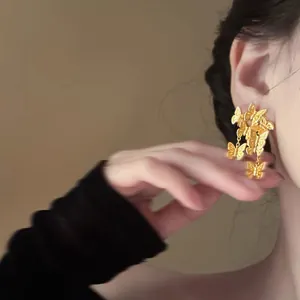 Nahaufnahme eleganter goldener Schmetterlings-Ohrstecker am Ohr eines Models