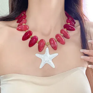 Detailaufnahme einer roten Acrylperlenkette mit einem weißen Seestern-Anhänger.