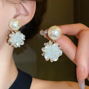 Primer plano de pendientes de flores y perlas con pétalos blancos elegantes y oro
