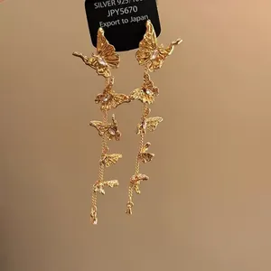 Makro-Detail französischer goldener Schmetterling-Quasten-Ohrringe mit Kristallen