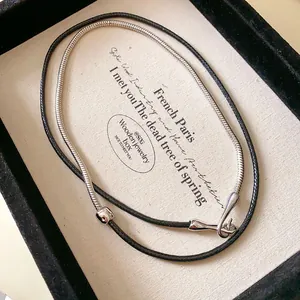Detail view of punk leather cord and silver snake chain necklace in jewelry box