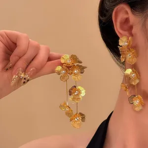 Detailansicht eleganter langer goldener Blumenohrringe mit funkelnden Kristallzentren