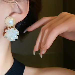 Primer plano de elegantes pendientes de flor blanca con perla en una modelo