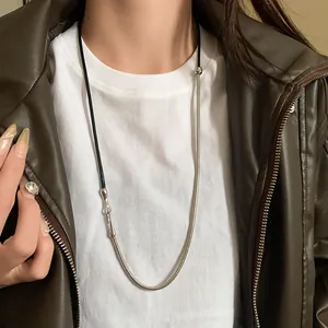 Macro detail of a punk leather cord and silver snake chain necklace worn by a model