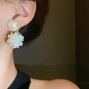 Vista detallada de un elegante pendiente de flor blanca y perla usado en la oreja