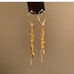 Dettaglio di eleganti orecchini pendenti dorati con petali a strati e ganci a goccia.