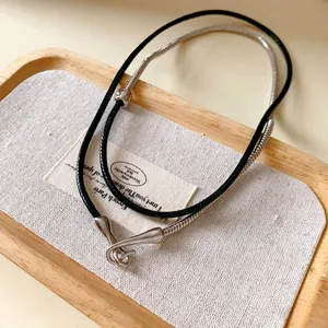 Detail of punk leather cord and silver snake chain necklace with irregular pendant