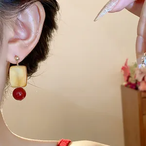 Close-up detail of a vintage style earring with square sugar cube and red glass bead