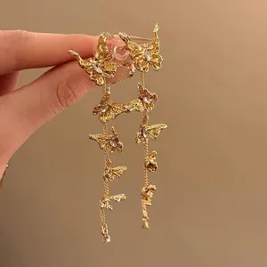 Detailansicht der goldenen Schmetterling-Ohrringe mit langen Quasten im Vintage-Stil