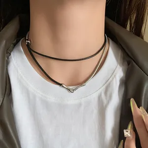 Close-up of punk layered necklace featuring black leather cord and silver snake chain.