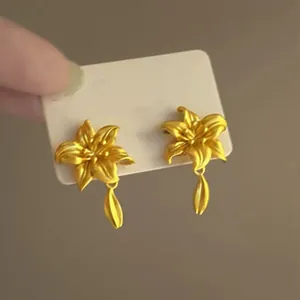 Detailansicht eleganter goldfarbener Lilien-Ohrstecker mit tropfenförmigen Anhängern