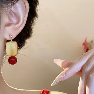Close-up of vintage square glass and red bead drop earring on model