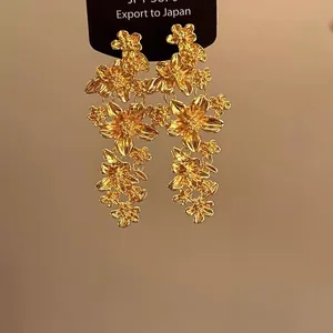 Detailansicht der französischen Vintage-Ohrringe mit goldenen Blumen auf schwarzer Karte.