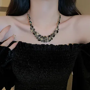 Detailed view of elegant gold-toned necklace with dark teardrop rhinestones on model