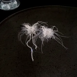 Close-up of elegant butterfly ear cuffs with white feathers and rhinestone tassels
