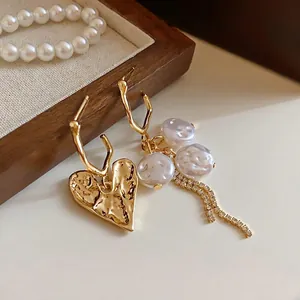 Elegant vintage gold heart earrings with pearls and crystal tassels on a dark wooden tray