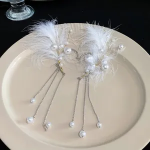 Vista detallada de estas orejeras de plumas blancas con perlas y borlas largas de plata