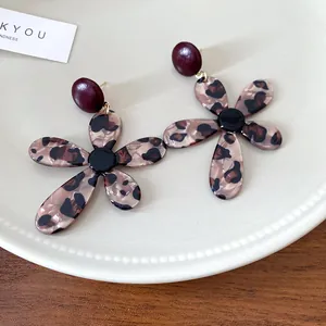 Close-up of vintage resin earrings with leopard print flower design on a white plate.