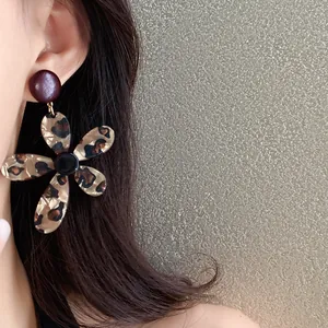 Detailed macro view of a vintage leopard print resin flower earring worn on ear