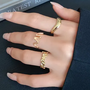Close-up detail of three elegant irregular gold geometric open rings worn on model hand