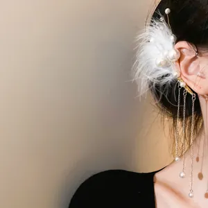 Detalle de un elegante pendiente de oreja con plumas blancas y borlas de perlas finas