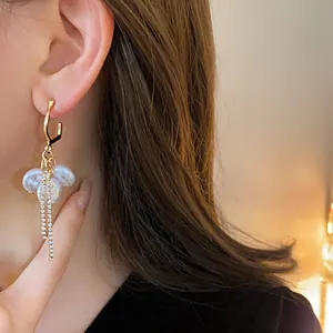 Close-up of elegant pearl earrings with rhinestone tassels and golden hoops shown on an Asian model
