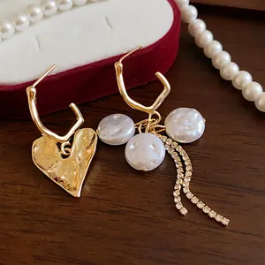 Detailed close-up showing asymmetric gold heart and pearl tassel earrings design