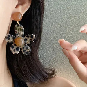 Macro view of a stylish resin leopard print flower earring on an Asian model's ear