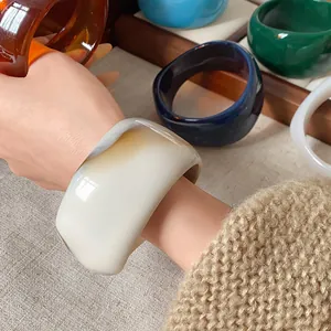 Dettaglio di bracciale largo in resina marmorizzata irregolare con trame uniche