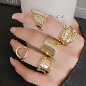 Detailed view of multiple gold-colored chunky irregular geometric open rings worn on fingers