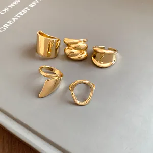 Close-up of five irregular gold-plated geometric open rings in various minimalist designs
