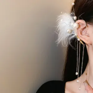 Primer plano detallado del ear cuff de plumas blancas y perlas con borlas de plata