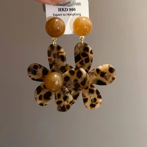 Close-up detail of vintage leopard print resin flower earrings with brown bead top