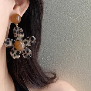 Close-up of leopard print flower resin earrings on model's ear