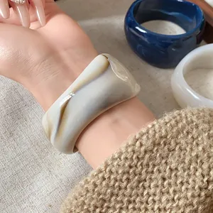 Dettaglio di un ampio bracciale a fascia irregolare con venature marmorizzate artistiche