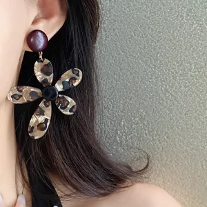 Close-up view of a retro leopard print resin flower earring worn by a female model.
