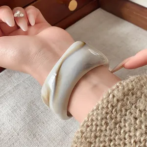 Vista dettagliata di un bracciale largo irregolare con trama marmorizzata al polso