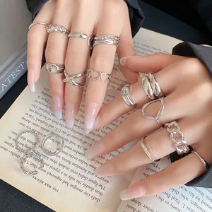 Close-up of stylish silver irregular geometric open rings on hands over an open book