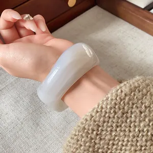 Primo piano di un bracciale rigido largo marmorizzato con finitura bianca.