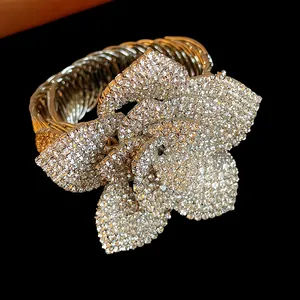Macro view of a multi-layer sparkling rhinestone flower on a golden twisted cable bangle
