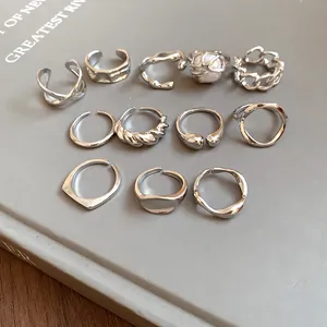 Collection of silver irregular geometric open rings displayed on a sleek grey book cover