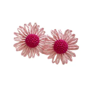 Bohemian style pink raffia woven daisy flower earrings featuring fuchsia beaded centers
