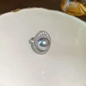 Dettaglio di anello vintage regolabile con perla grigia e cristalli lucenti