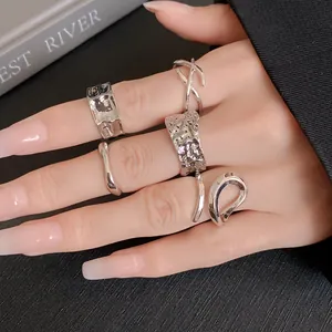 Detail shot showing a variety of irregular geometric silver rings on a model's hand
