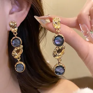 Elegant vintage gold drop earrings with blue resin centers on a model.